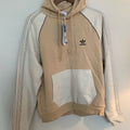 Beige and white Adidas hoodie with a tag on a light gray background
