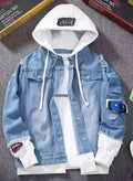 Blue denim jacket with white hoodie on a gray surface