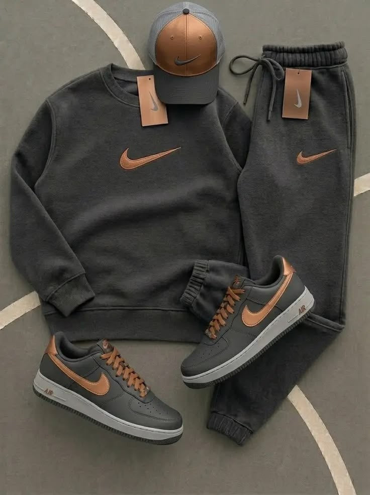 Gray Nike sweatshirt, jogger pants, and sneakers with brown accents on a gray surface.