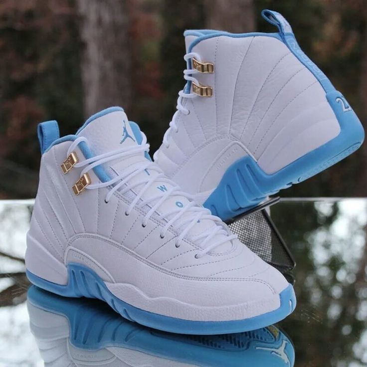 White and blue high-top sneakers with gold accents on a reflective surface.